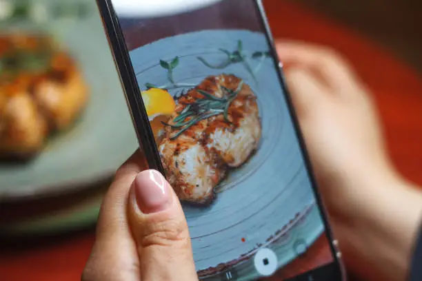 Photo of Woman hands taking food photo by mobile phone, selective focus