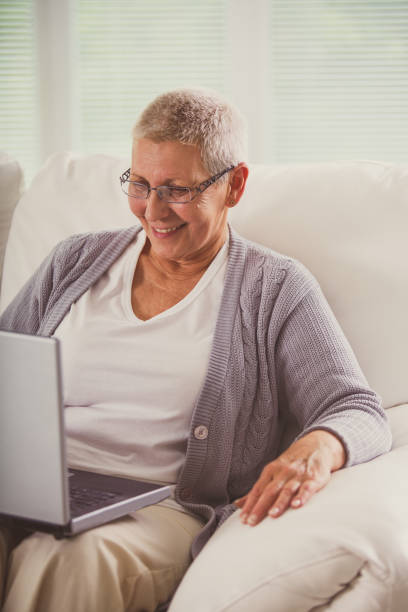 istock Cheerful senior woman having fun while browsing internet on her laptop 1178451623