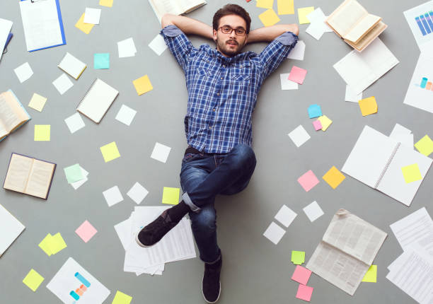 istock Young man isolated on grey background with papers and notes relaxed looking camera 1178452005