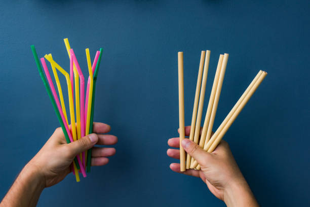 One hand holds colourful plastic straws and another hand holds bamboo straws. Good background for ecology topics One hand holds colourful plastic straws and another hand holds bamboo straws. Good background for ecology topics biodegradable photos stock pictures, royalty-free photos & images
