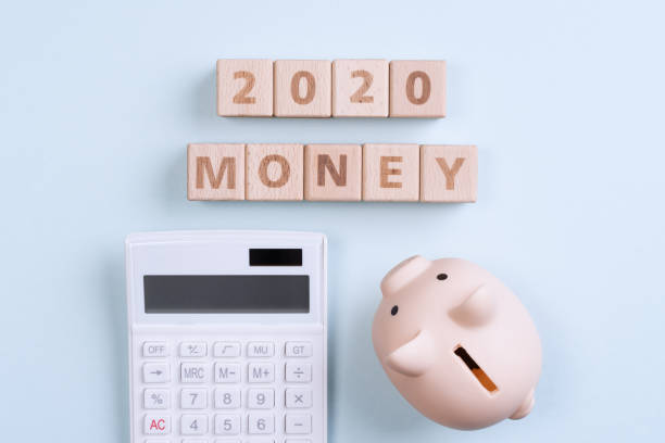 istock Abstract 2020 financial goal design concept - geometric wood blocks cubes on blue table background with piggy bank. 1178458285
