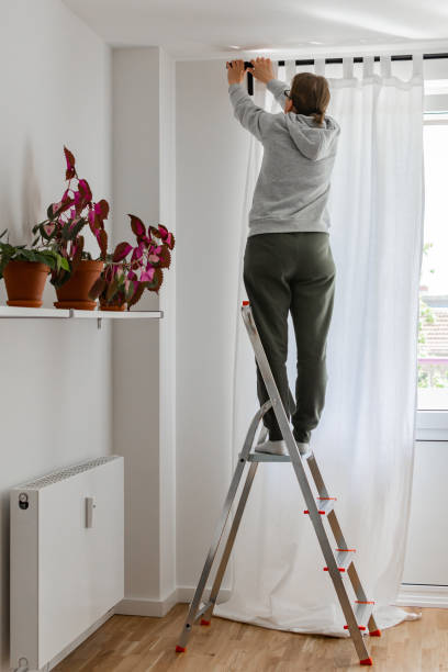 istock Woman hangs white curtains on the curtain rod 1178458520