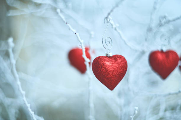 istock Heart shaped Christmas ornaments on snowy branches 1178459306