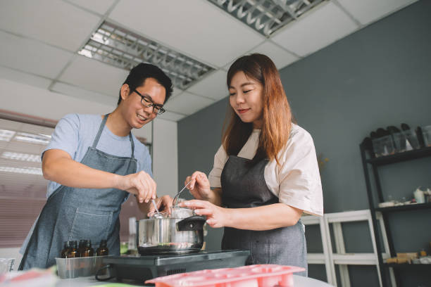 istock 2 asian chinese female and male working on handmade soap making workshop in a studio and mixing the raw material and cooking it 1178463435