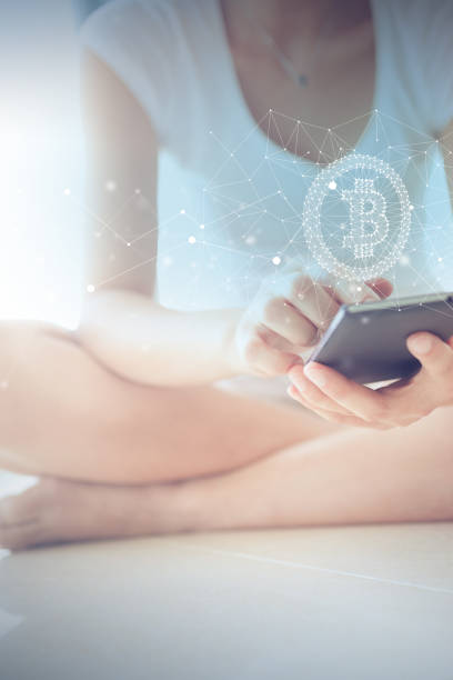 istock Woman Sitting on Floor Using Smart Phone with Bitcoin Symbol Floating on Screen 1178468612