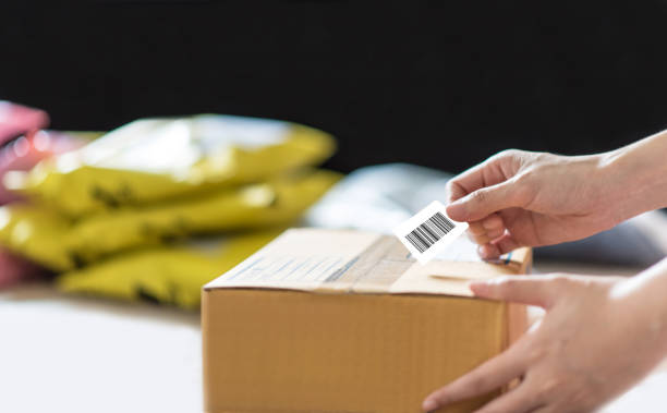 hand holding barcode label on shipping box - parcel label imagens e fotografias de stock