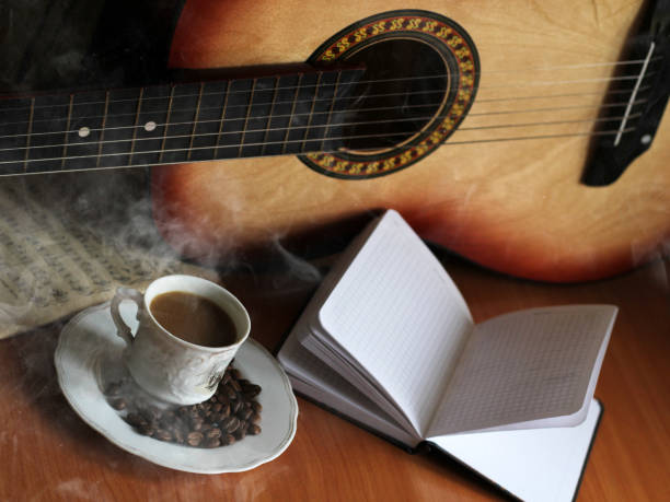 Coffee cup and guitar on wooden table, music