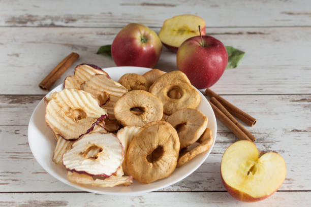 Dried apple rings and apple crisp chips in comparison with fresh red apples. Healthy eating, dieting concept.