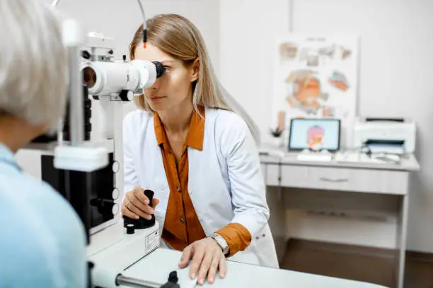 Ophthalmologist examining eyes of a senior patient using microscope during a medical examination in the ophthalmologic office