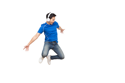 Young happy Asian man listening music and jumping with smile isolated on white background