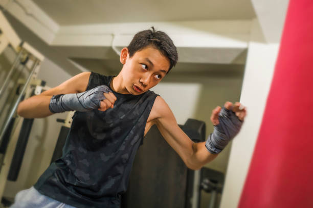 азиатский американский подросток бокс на тренажерный зал . молодой красивый и жестокий 13 или 14 лет мальчик в запястье обертывания делать бо - 13 14 years стоковые фото и изображения