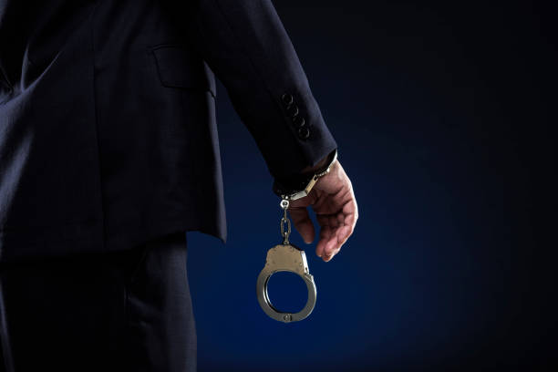 handcuffs hanging on a hand on gray wall background