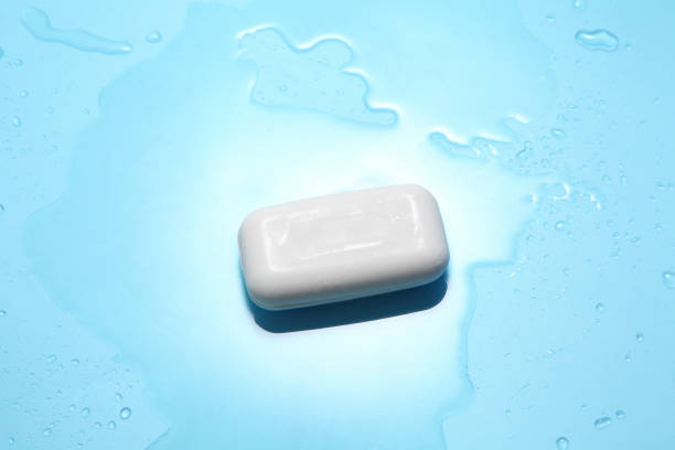 le savon blanc et la baisse d'eau sur un fond bleu avec un espace vide pour un texte, accessoires de douche dans la vue supérieure - bar of soap photos et images de collection