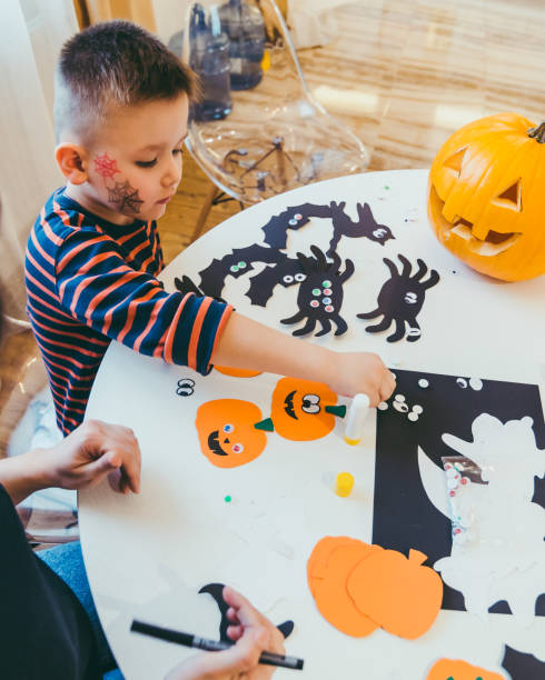 jeune mère avec le fils d'enfant en bas âge faisant des citrouilles d'artisanat pour le temps de famille de vacances d'halloween - spider mum photos et images de collection