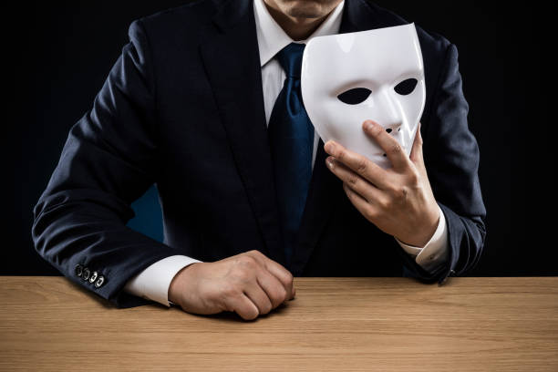 istock Man in a suit removes his mask 1178499375