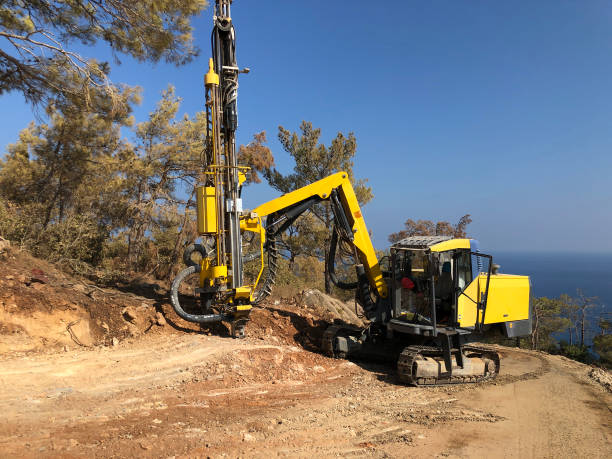 la maquinaria amarilla está perforando agujeros en la parte superior del acantilado de mar rocoso durante las operaciones de perforación de agujeros de explosión - drill mining rock borehole fotografías e imágenes de stock