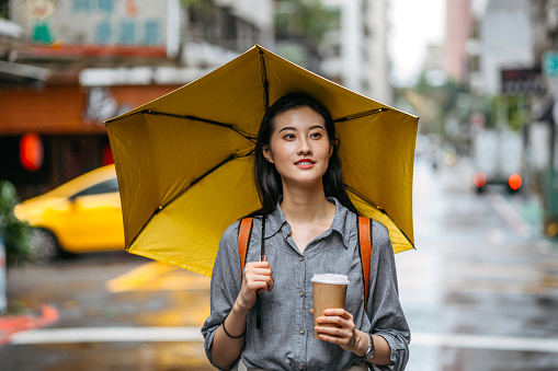 Woman with umbrella and coffee on rainy day