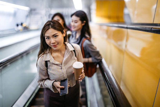 mujer en escaleras mecánicas con teléfono móvil y café - escalator steps staircase moving up fotografías e imágenes de stock