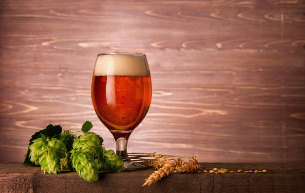 Dark beer glass with foam and green hop plant cones on wooden background with copy space Dark beer glass with foam and green hop plant cones on wooden background with copy space india pale ale photos stock pictures, royalty-free photos & images