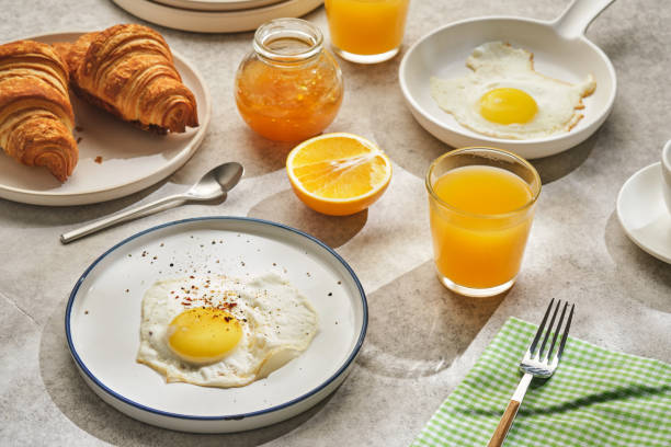 istock Continental breakfast. Fried eggs and sausage with croissants and orange juice. 1178506209