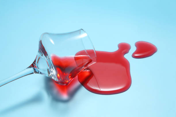 istock Red wine spilled from glass over blue background with a blank space for a text,  Red wine spilled on color table 1178508969