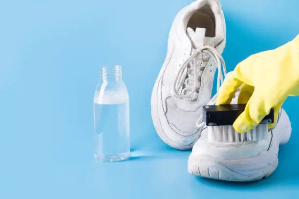 Photo of Dirty white sneakers with special tool for cleaning them on blue.