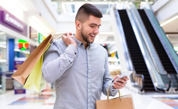 istock Cheerful man chatting on cellphone in shopping mall 1178513819