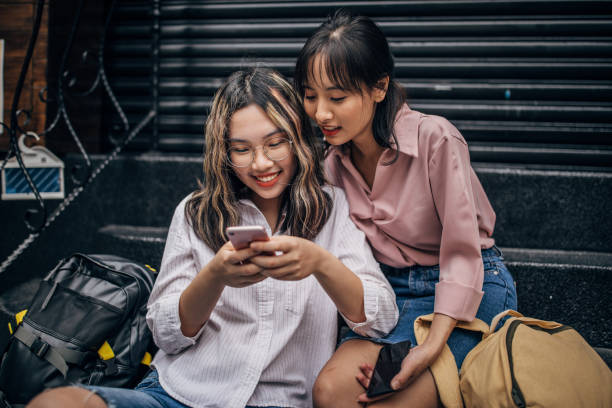 istock Two cute women sitting on steps and using smart phone 1178514611