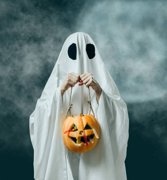 istock Halloween white ghost holding pumpkin basket with candies. 1178519379