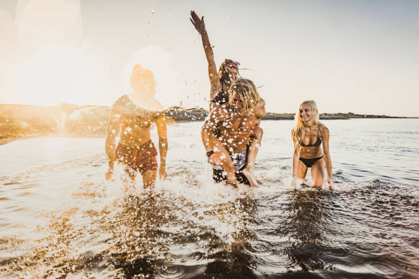 istock Carefree friends having fun while running through sea at sunrise. 1178520413