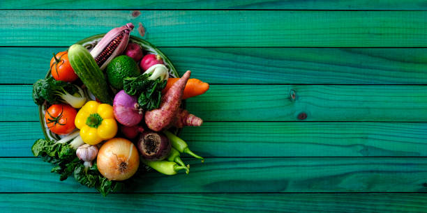 verduras orgánicas frescas en un cuenco de madera redondo antiguo sentado sobre un viejo fondo de mesa con paneles de madera de color turquesa, rodado directamente por encima con luz natural, con un buen espacio de copia a la derecha de la imagen. - contrasts viewpoint wood wood panelling fotografías e imágenes de stock