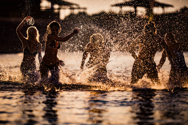 istock Group of happy people having fun while playing in the sea at sunset. 1178520980