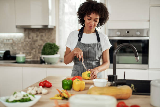 istock Woman cutting yellow bell pepper while standing in kitchen at home. 1178523429