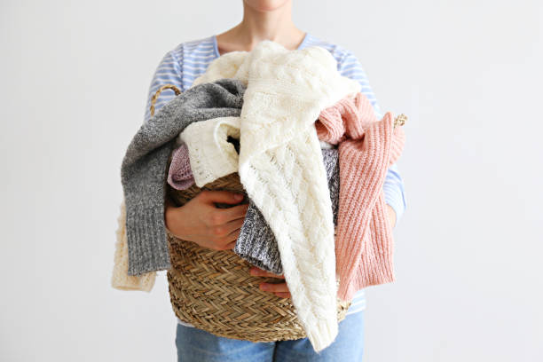 pile de chandails tricotés de différentes couleurs et motifs parfaitement empilés sur les mains de la femme. - pull cachemire femme photos et images de collection