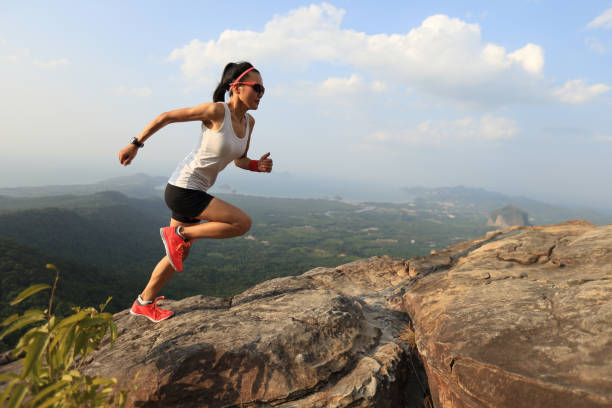 산 봉우리에 달리는 젊은 아시아 여자 주자 - climbing rock climbing women determination 뉴스 사진 이미지