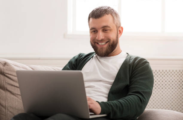 istock Smiling man working on laptop online at home 1178529552