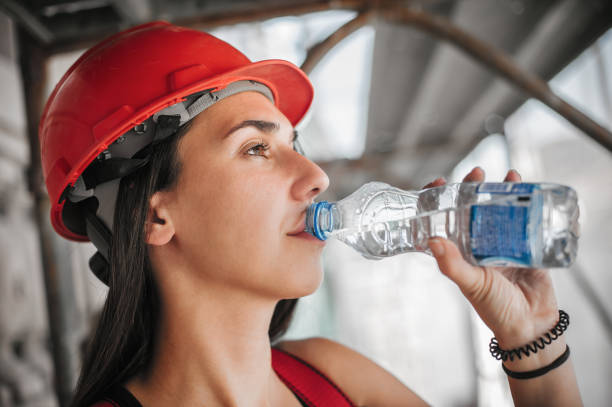 istock Female construction mason worker on scaffolding, resting and drinking water 1178531171