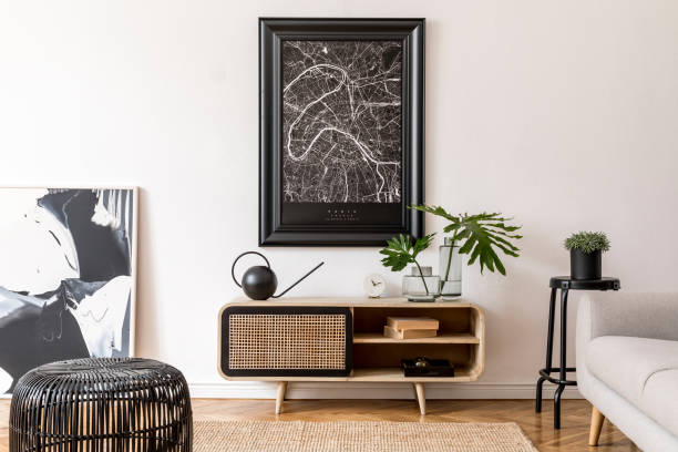 istock Modern scandinavian living room interior with black mock up poster map frame, design commode, sofa, black chair plants, tropical leaf, books and elegant accessories. Template. Stylish home decor. 1178532743