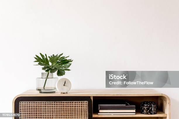 Interior Design Of Living Room At Scandinavian Apartment With Stylish Commode Tropical Leaf In Vase Books White Clock And Elegant Accessories Modern Home Decor Template Copy Space White Walls Stock Photo - Download Image Now