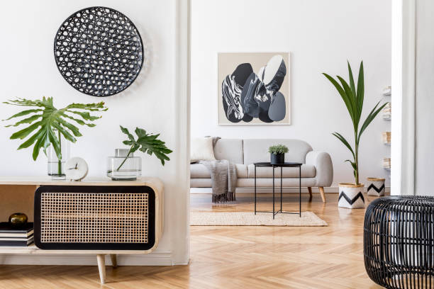 istock Scandinavian and design home interior of open space with wooden commode, gray sofa, design black rattan decoration, tropical leafs and elegant personal accessories. Stylish art home decor. Template. 1178534520