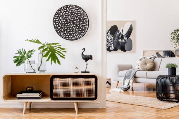 istock Scandinavian and design home interior of open space with wooden commode, gray sofa, design black rattan decoration, tropical leafs and elegant personal accessories. Stylish art home decor. Template. 1178534737