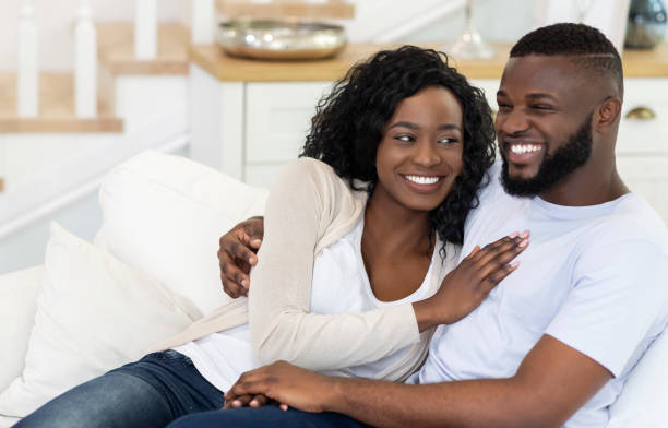 istock Happy black couple sitting on couch at home, cuddling 1178534906