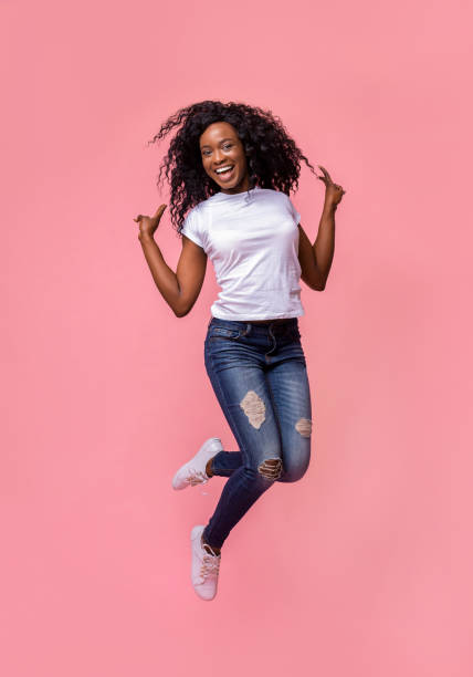 istock African american joyful lady jumping and gesturing peace 1178535864