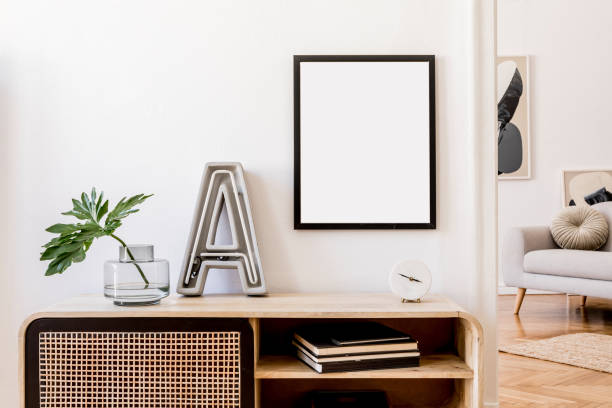istock Modern scandinavian home interior with mock up photo frame, design wooden commode, big cement letter, tropical leaf, gray sofa and personal accessories. Stylish home decor. Template. Ready to use. 1178536764