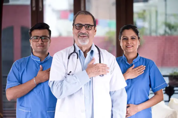 Photo of Doctor and nursing staff with hands on chest