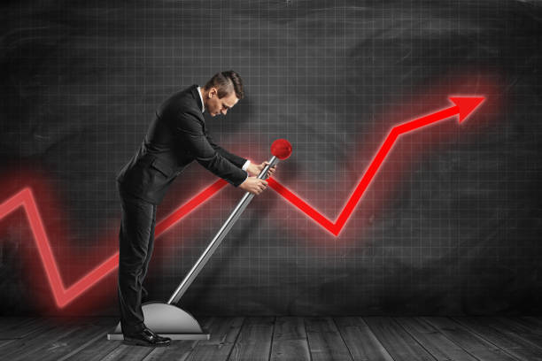 Side view of businessman looking down and pulling big lever near black graph ruled wall with red graph arrow on it.