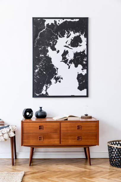istock Minimalistic composition of living room with mock up poster frame, wooden retro commode, footrest, rattan basket and elegant personal accessories. Vintage home decor. Template. 1178539496