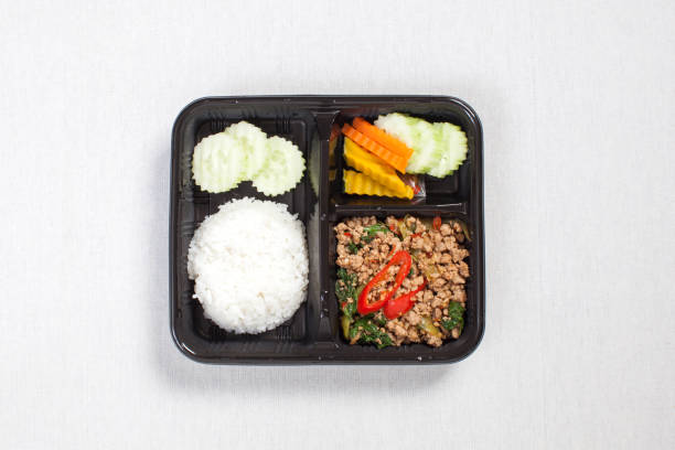 istock Basil fried rice with minced pork, put in a black plastic box, put on a white tablecloth, food box, Spicy fried pork with basil leaves, Thai food. 1178540060