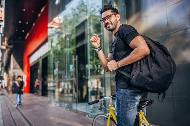 Handsome man riding bicycle in city One man, sitting on his bicycle on the street downtown. urbane stock pictures, royalty-free photos & images