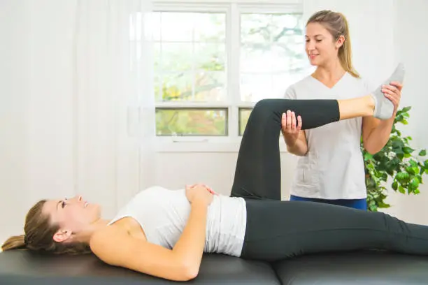 Photo of A Modern rehabilitation physiotherapist at work with client. Working on shoulder.